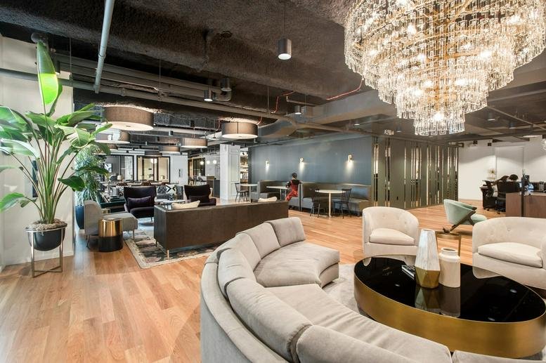Spacious lounge area with a large crystal chandelier, curved sectional sofa, and wood flooring.