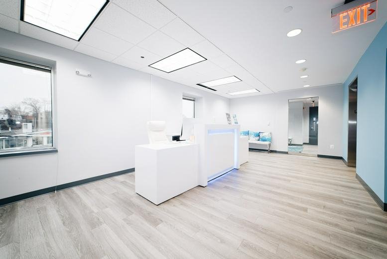 Reception area at 12345 Parklawn Drive, Suite 200 with a white desk, wood-style flooring, and blue accent wall.