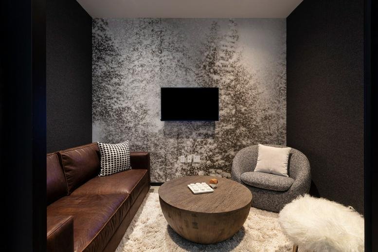 Cosy lounge room with a leather sofa and a forest mural at 125 High Street.