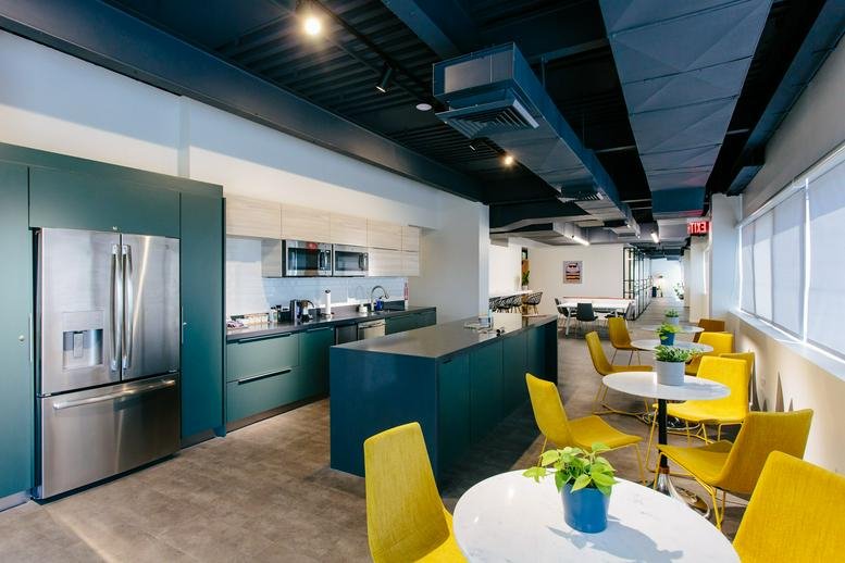 Spacious communal kitchen and dining area with teal cabinetry and yellow chairs at 1250 Avenida Ponce de Leon.