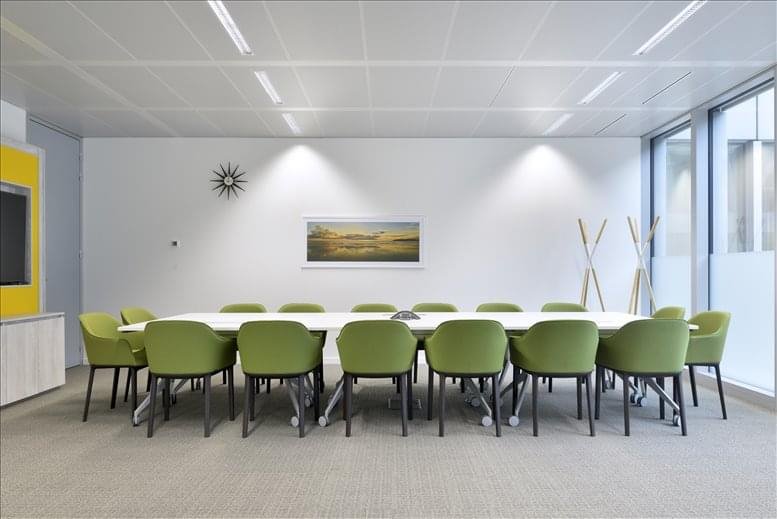 Meeting room with green chairs around a long table and wall-mounted artwork.