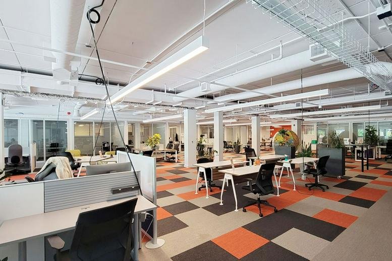 Spacious modern office at 1295 North Service Road with colorful geometric carpeting and white exposed ceilings.
