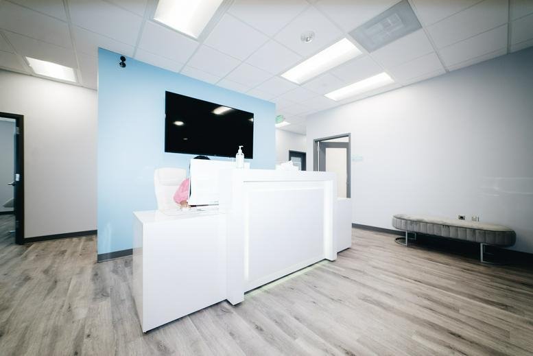 Reception area with white desk and large wall-mounted TV.