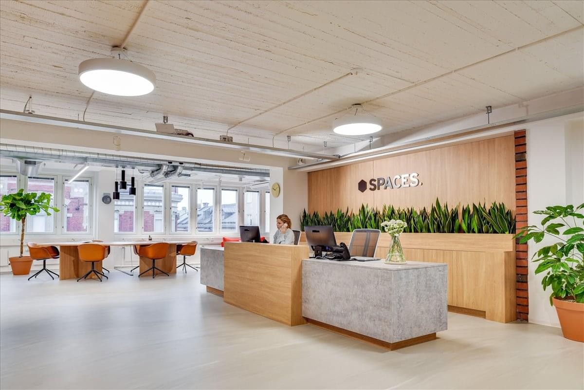 Spacious reception area at 132 West 31st Street, Penn Plaza with wooden desk, greenery, and hanging lights.