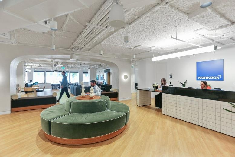 Reception desk with white tiled facade and green velvet circular seating.