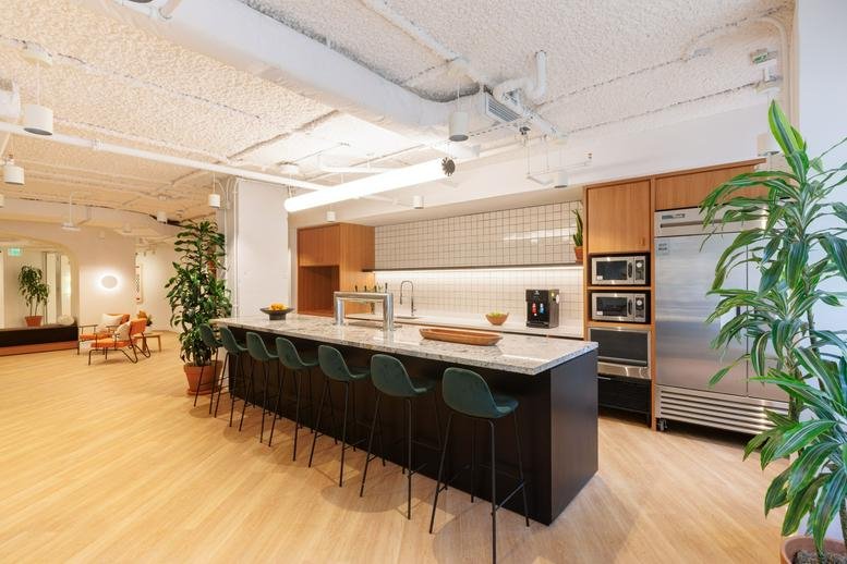 Communal kitchen area with a marble countertop and green stools.