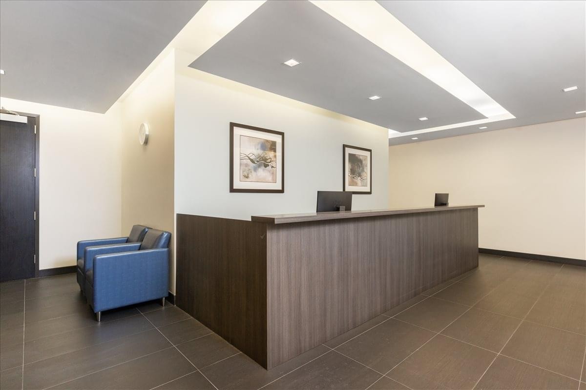 Modern reception area at 14 Penn Plaza, 225 West 34th Street with dark wood desk and blue chairs.