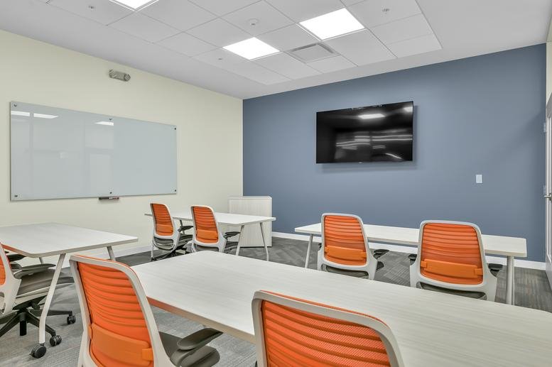 Bright training room at 14150 Huffmeister Road with orange chairs, whiteboards, and a wall-mounted TV.