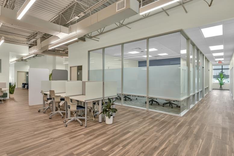 Spacious open-plan interior of 14150 Huffmeister Road, Suite 200, with wood floors and glass-walled meeting rooms.