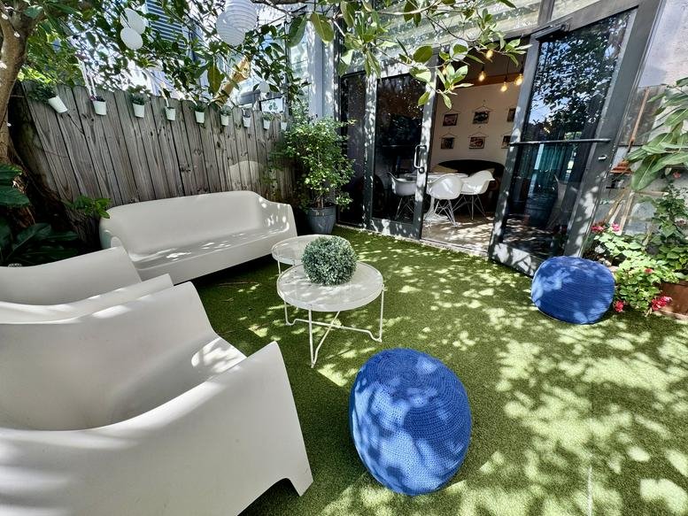 Lush outdoor patio at 142 NW 37th St with white lounge seating and vibrant greenery.