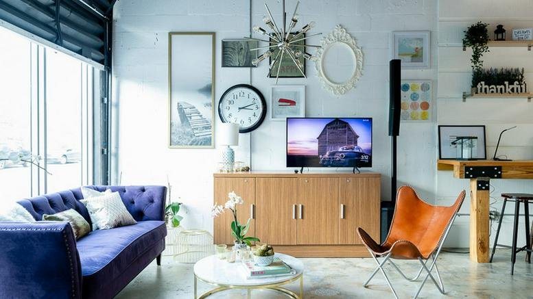 Lounge area at 142 NW 37th St with a purple sofa, mid-century chair, and eclectic wall art.