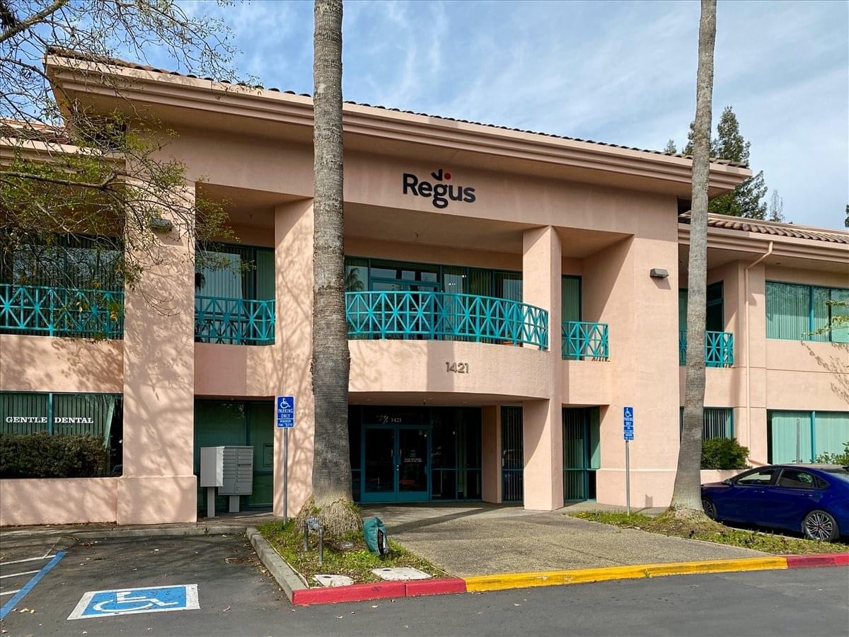 Exterior view of the peach-colored office building at 1421 Guerneville Road with palm trees.