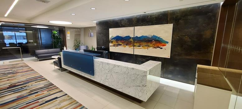 Modern marble and wood reception desk at 144 4th Ave SW, Suite 2100 with mountain artwork.
