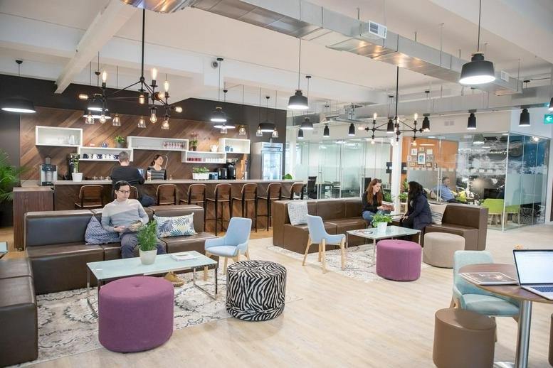 Lively coworking space with lounge seating, colorful ottomans, and a coffee bar.