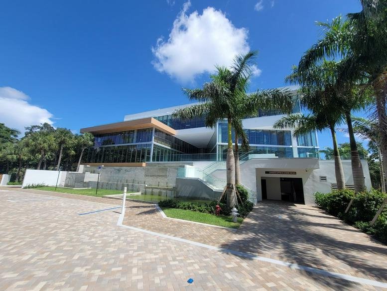 Modern building exterior at 1489 West Palmetto Park Road showing glass facade and palm trees.