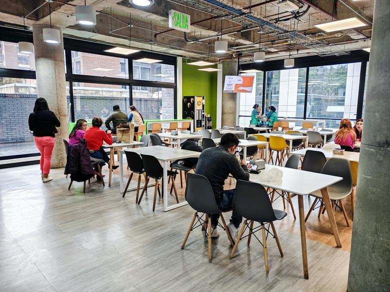 Bright communal cafeteria and lounge area with colorful seating and floor-to-ceiling windows.