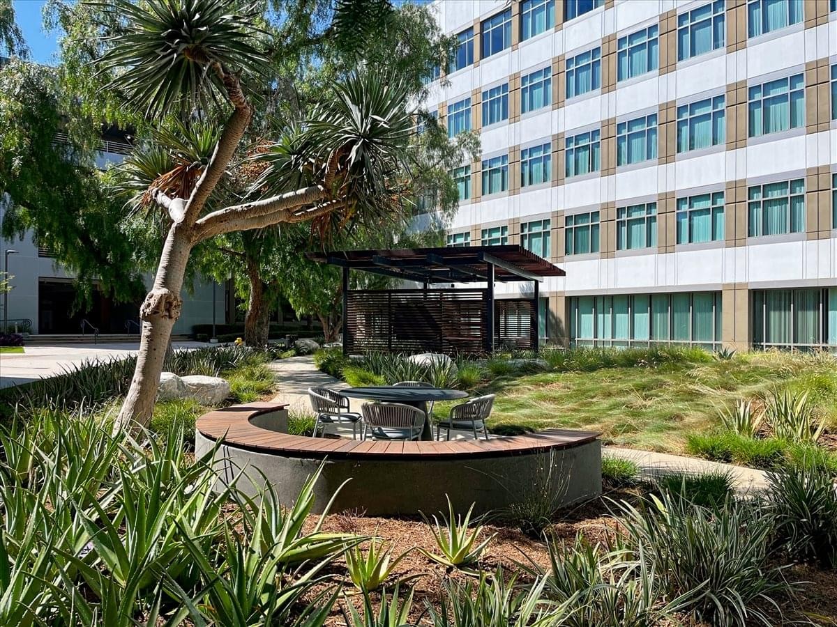 Modern multi-story office building at 15 Enterprise with a landscaped courtyard and outdoor seating.