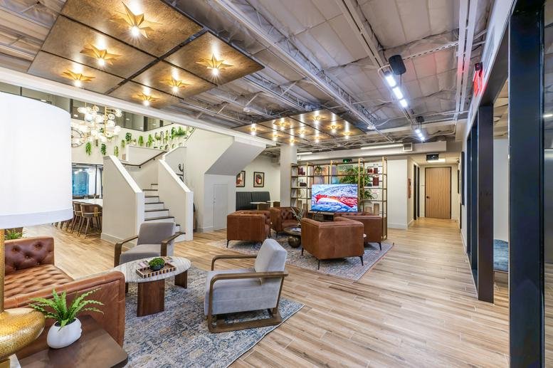 Spacious lounge area with leather armchairs, wood flooring, and a decorative ceiling with warm lighting.