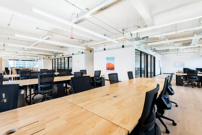 Spacious open-plan workspace at 1600 7th Avenue, Suite 1100, Westlake with large wooden desks and industrial ceiling.