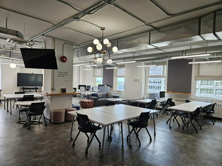 Spacious open-plan coworking area at 167 Lombard Avenue with multiple tables and modern lighting.