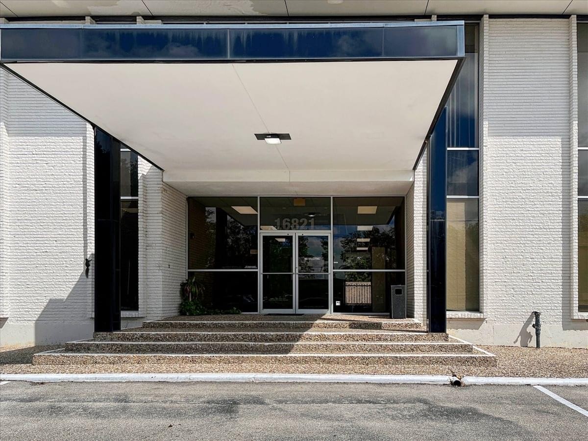 Modern glass entrance of the Atlas Building at 16821 Buccaneer Lane.