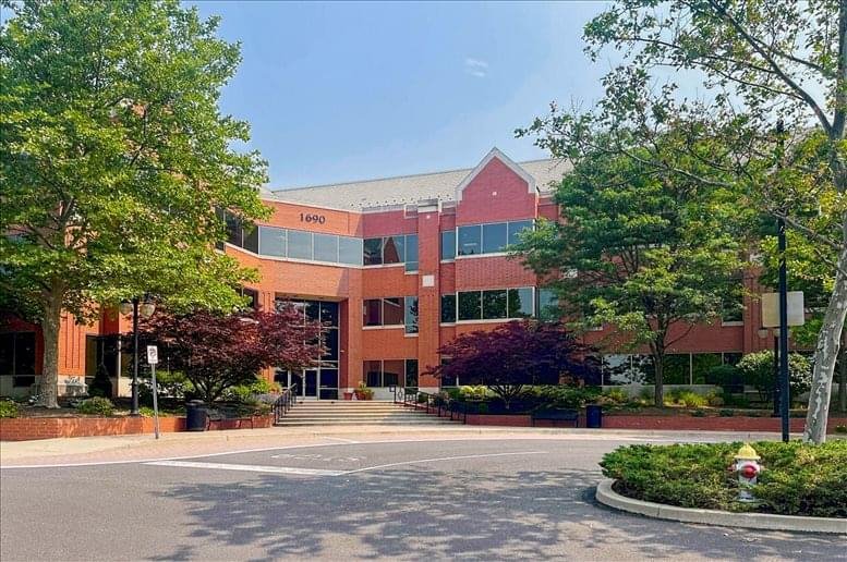 Wide view of the brick office building exterior surrounded by green trees.