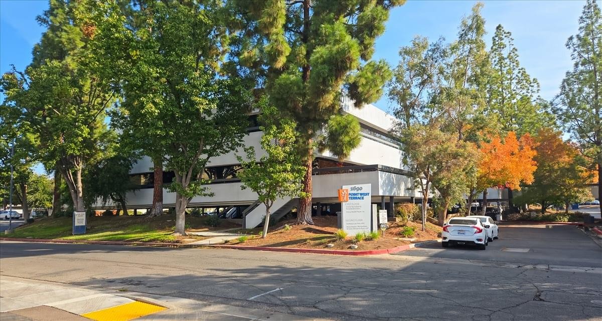 Exterior view of the multi-story office building at 1690 W. Shaw Avenue surrounded by lush green trees.