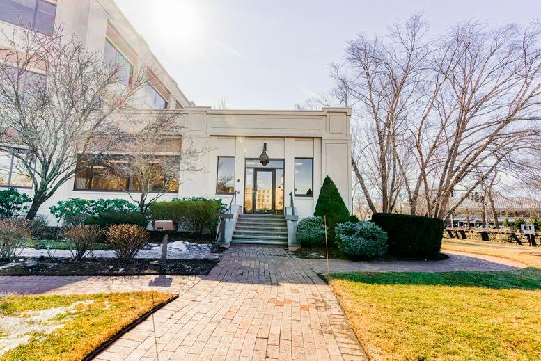 Exterior entrance of the 1700 East Putnam Avenue building with stone facade and landscaped stairs.