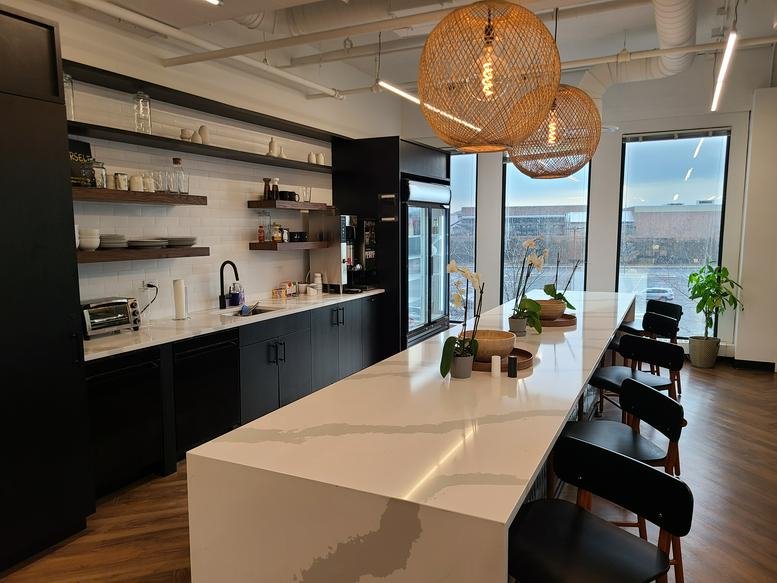 Modern kitchen and breakroom area with a white marble island and woven pendant lights.