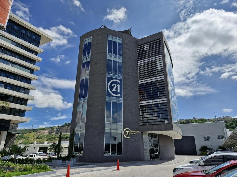 Exterior view of the modern glass-fronted 1716, Avenida 5 de Febrero building under a blue sky.