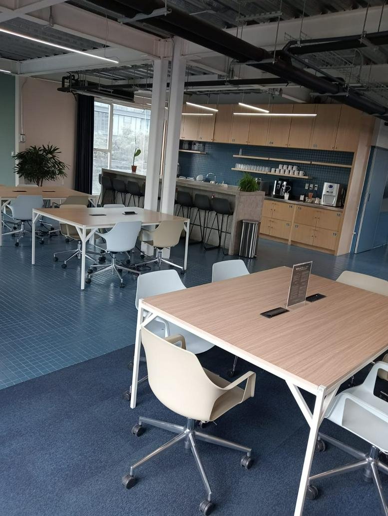 Spacious communal coworking space at 174, Liverpool, Juárez, Mexico City with wooden tables and kitchen area.