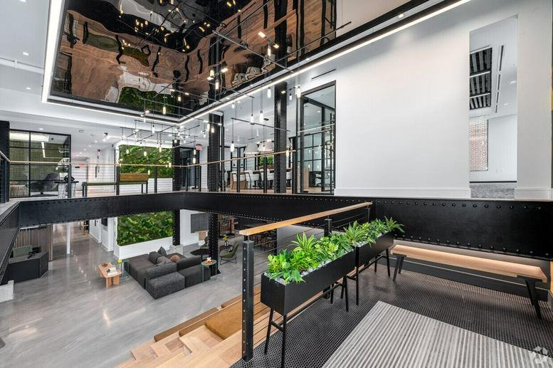 Spacious bi-level lobby with mezzanine, black steel accents, and indoor greenery at 1763 Columbia Road NorthWest.