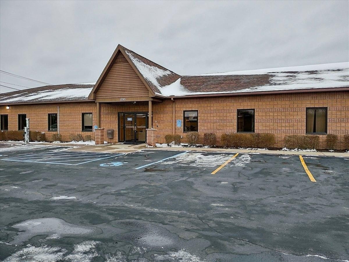 Exterior brick building at 1795 Baseline Road, Grand Island, New York with snow-dusted roof and large parking lot.