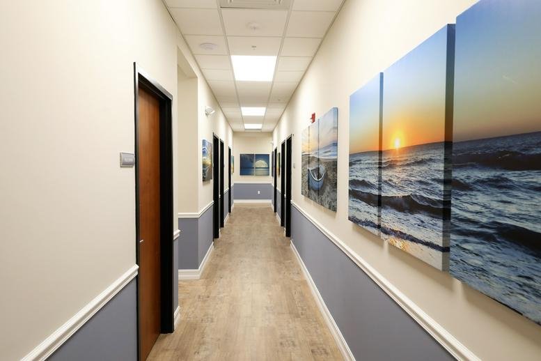 Long office corridor at Westview Plaza II featuring wood-look floors and vibrant ocean-themed wall art.