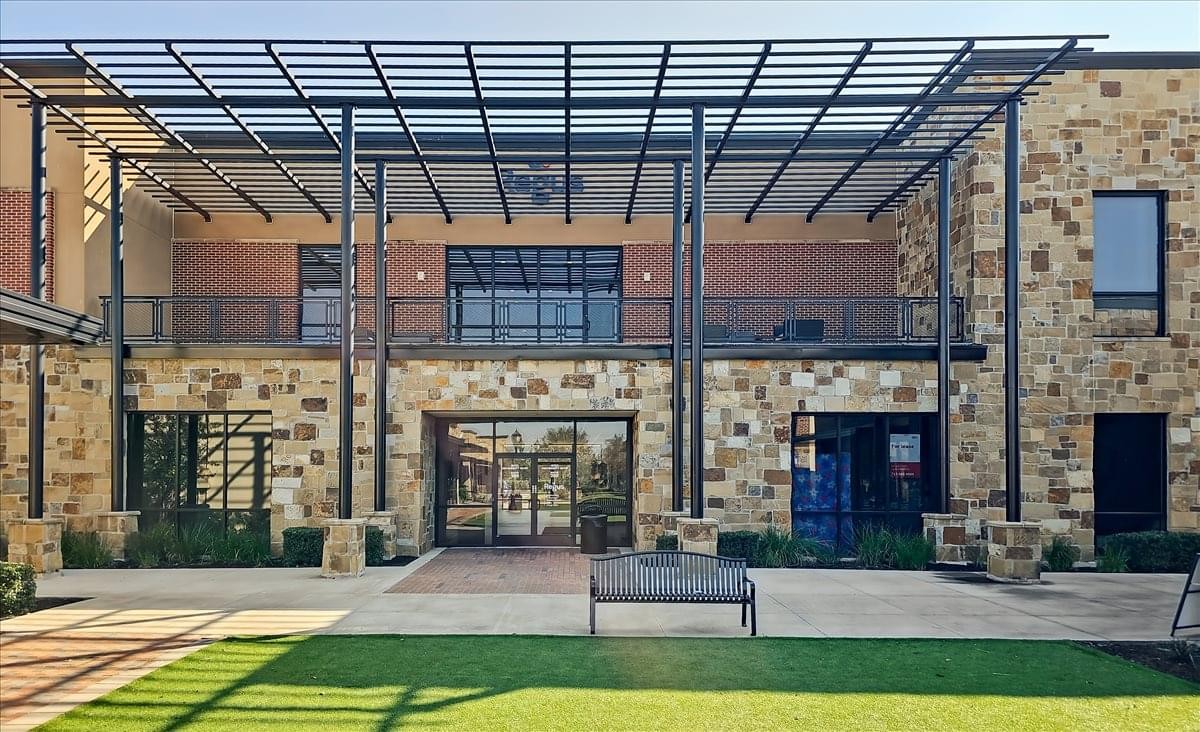 Modern stone facade and shaded courtyard entrance at 18722 University Boulevard, 2nd Floor, Suite 200.