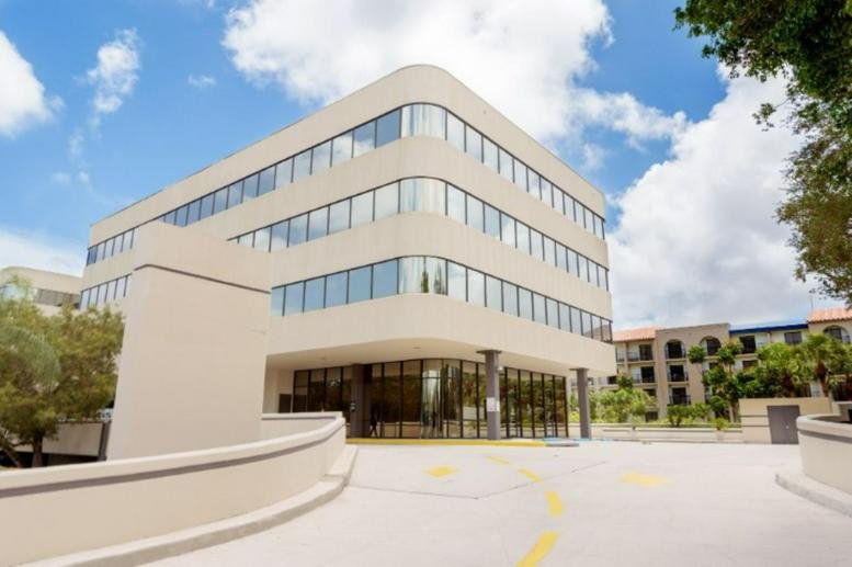 Exterior view of the white tiered building at 1900 Glades Road, Suite 500.