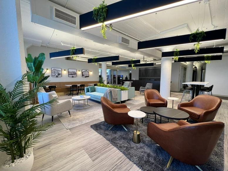 Spacious lounge area with brown leather armchairs, a blue sofa, and indoor plants.