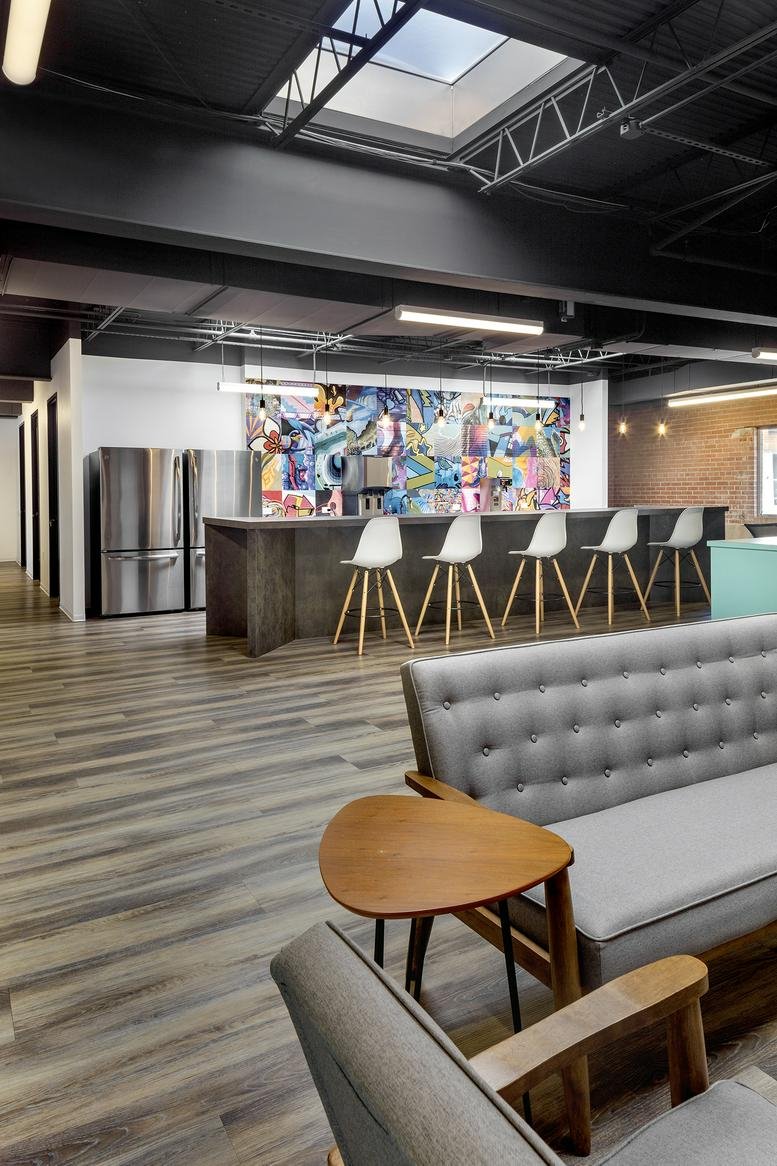 Spacious breakout area at 1923 Washington Ave with a colorful mural, breakfast bar, and vaulted skylight.