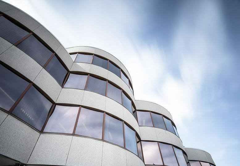 Curved modern exterior of the glass and stone building at 1940 Eglinton Ave E, 4th Floor, Toronto, Ontario.