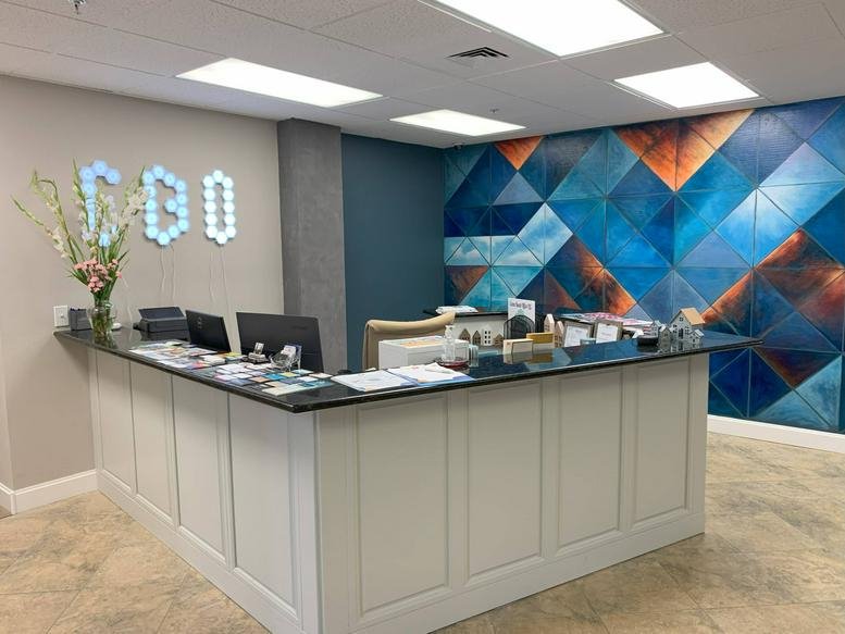 Bright reception desk with white paneling and a vibrant blue geometric feature wall.