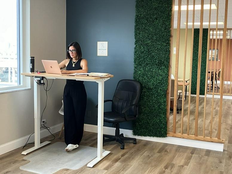 Bright standing desk workstation against a deep blue feature wall.