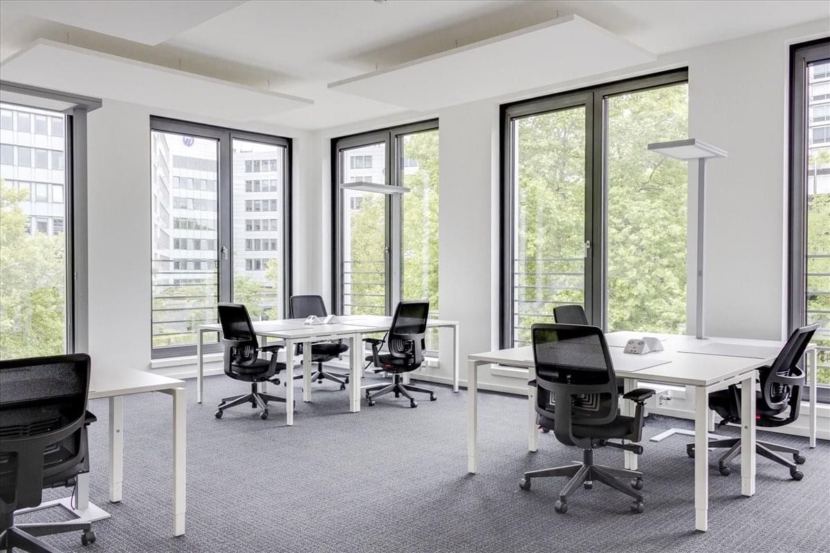 Office area with multiple desks and large windows.