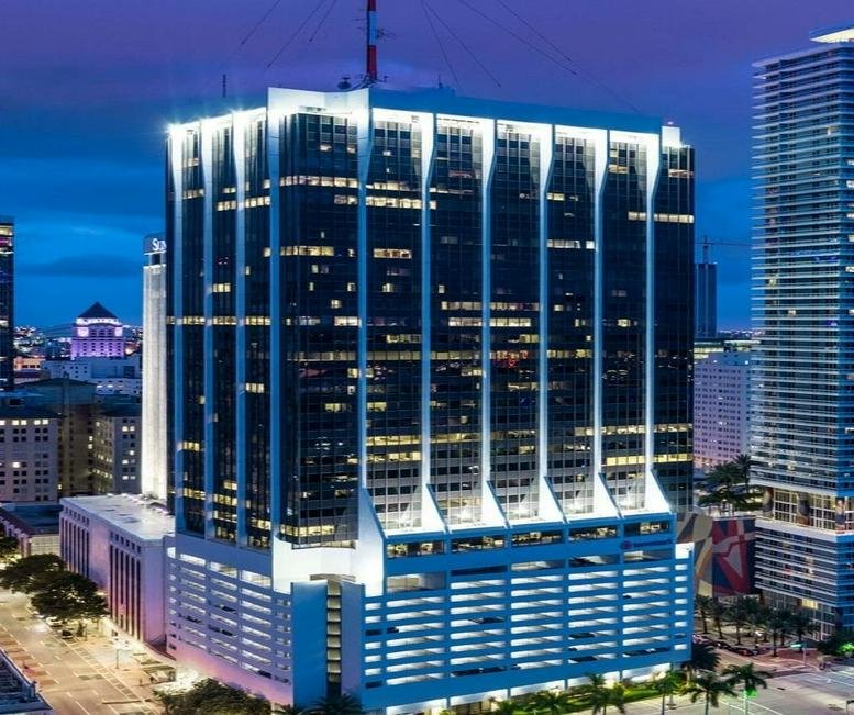 The illuminated facade of One Biscayne Tower showcasing its modern architecture at dusk.