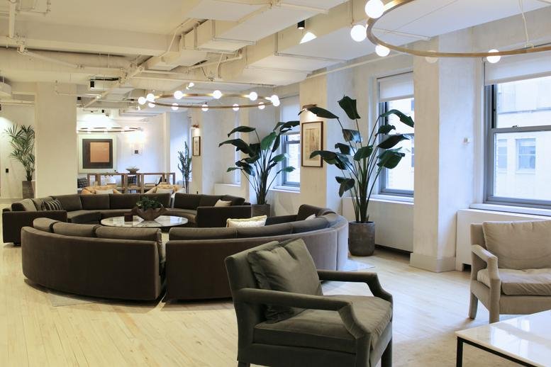 Spacious communal lounge at 20 North Wacker Drive with curved sofas and large potted plants.