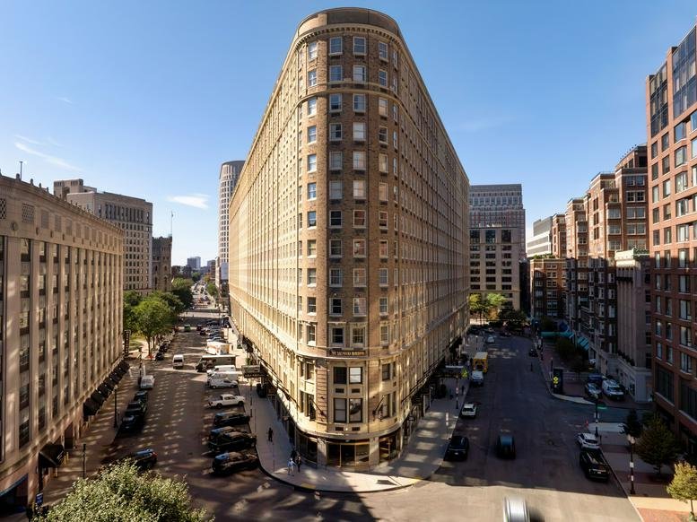 Wide-angle street view of the iconic wedge-shaped building facade against a clear blue sky.