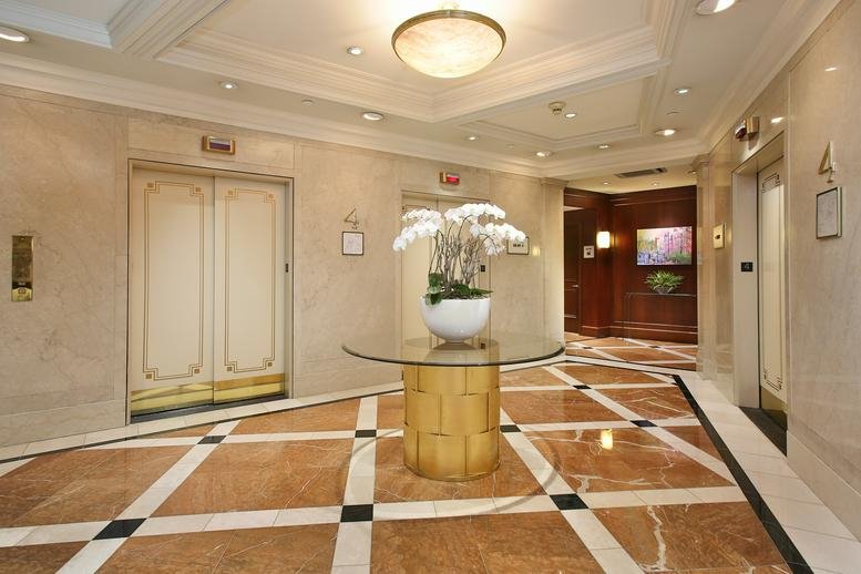 Elegant marble elevator lobby at 20 Park Plaza, 4th Floor with a central glass table and floral arrangement.