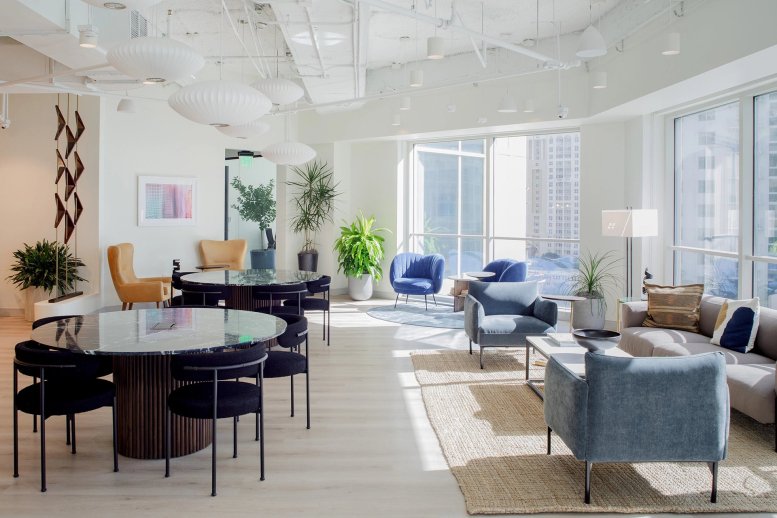 Sunlit communal lounge with marble tables, mid-century modern chairs, and city views.