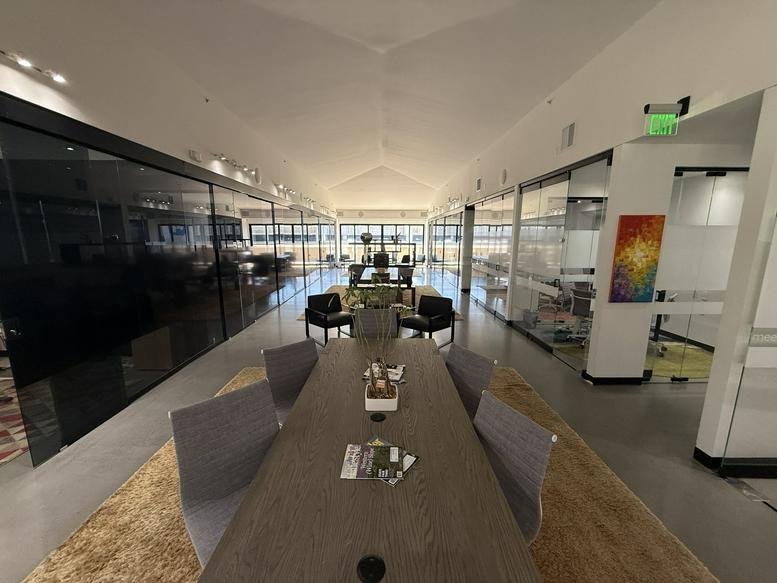 Spacious communal area at 201 Columbine Street, Suite 300 with a long wooden table and glass-walled offices.