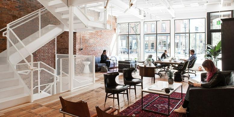 Spacious open-plan lounge with brick walls, white staircase, and natural light.