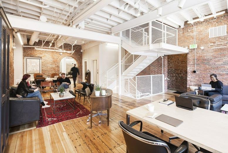 Spacious open-plan workspace featuring wooden floors and an industrial white staircase.